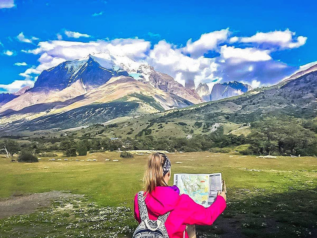 Female solo travel: A woman looks at a map with mountains in background